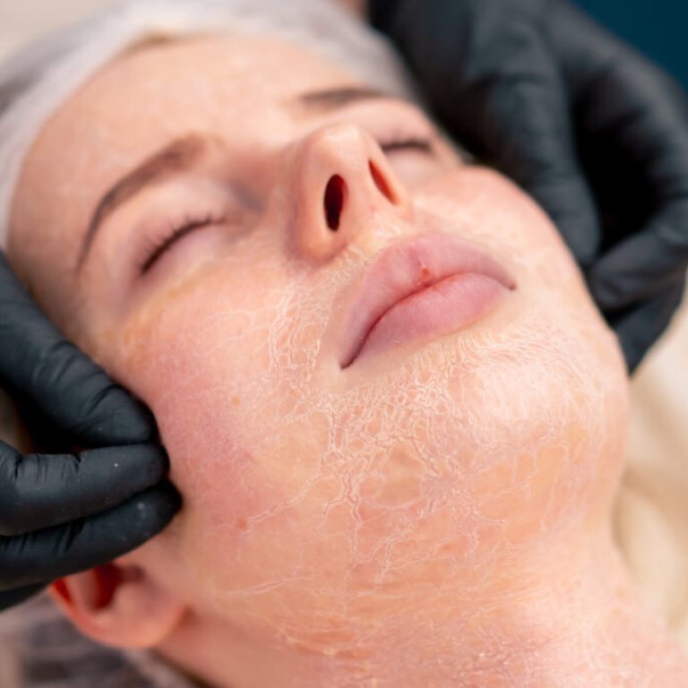 close-up beautician in gloves rubs the serum with massage movements on the face of client in salon